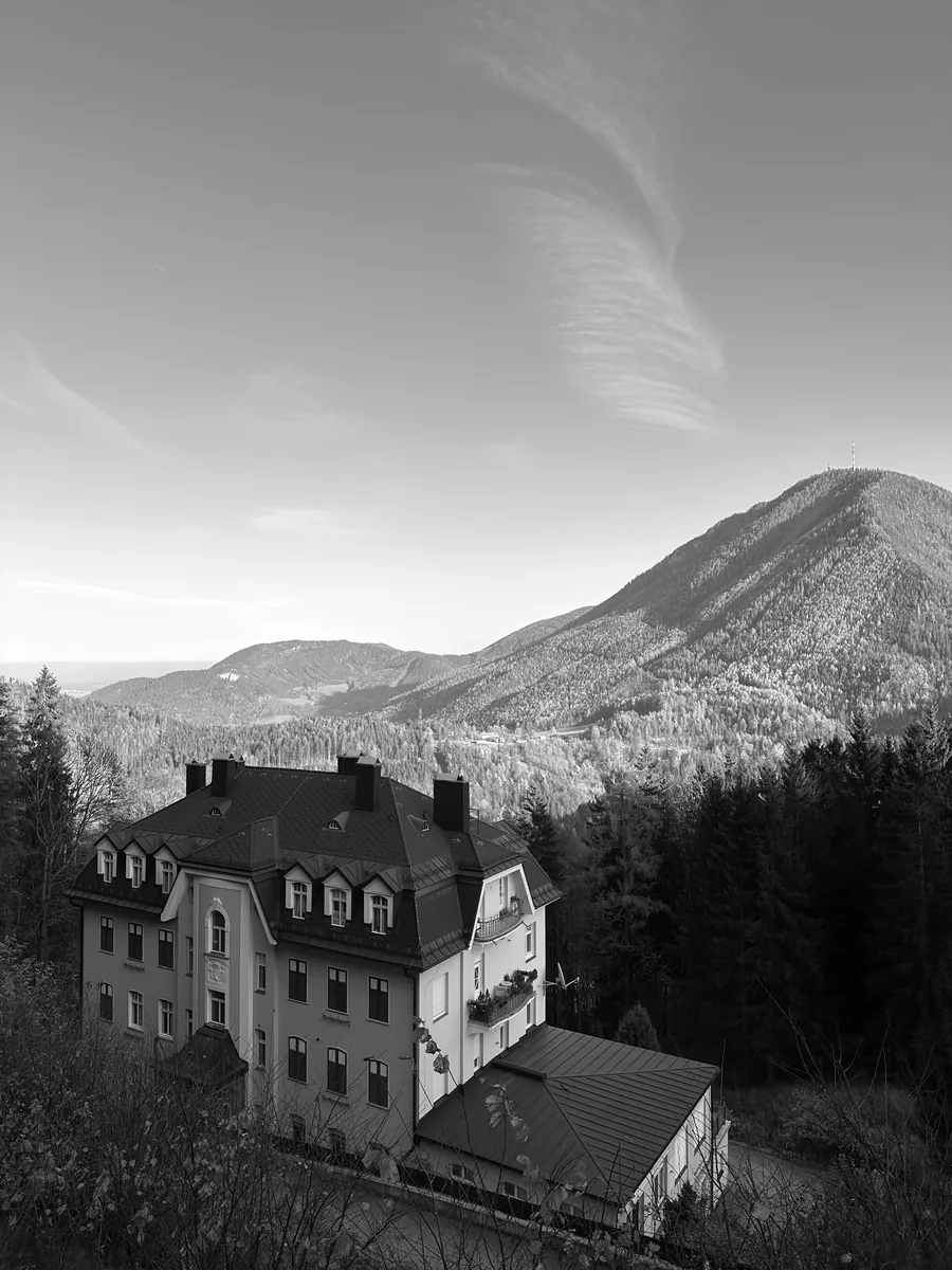 An old villa on the wooded slope, mountains behind